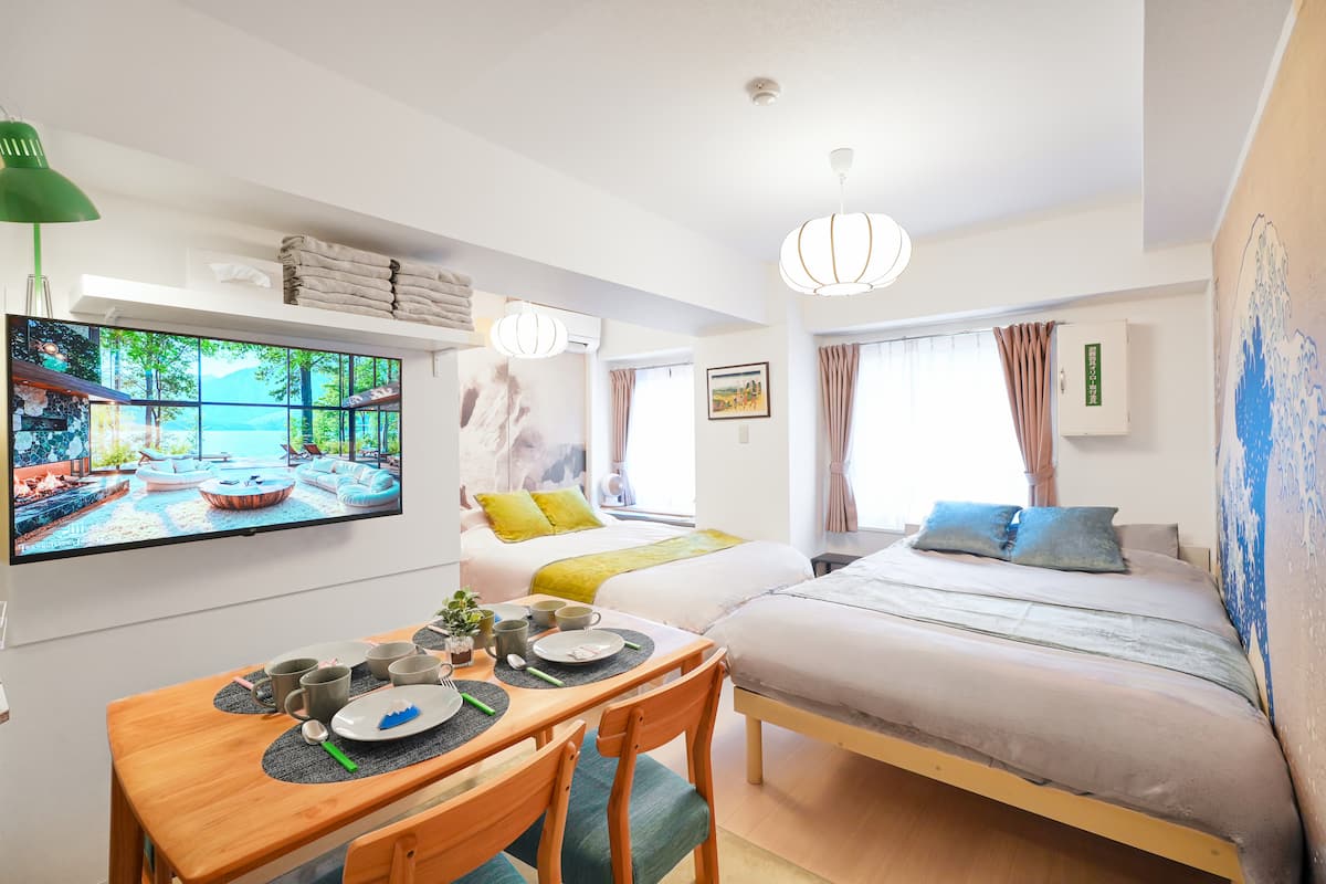 Sugamo Yasu Hotel — living and dining area with twin beds, dining table, and TV
